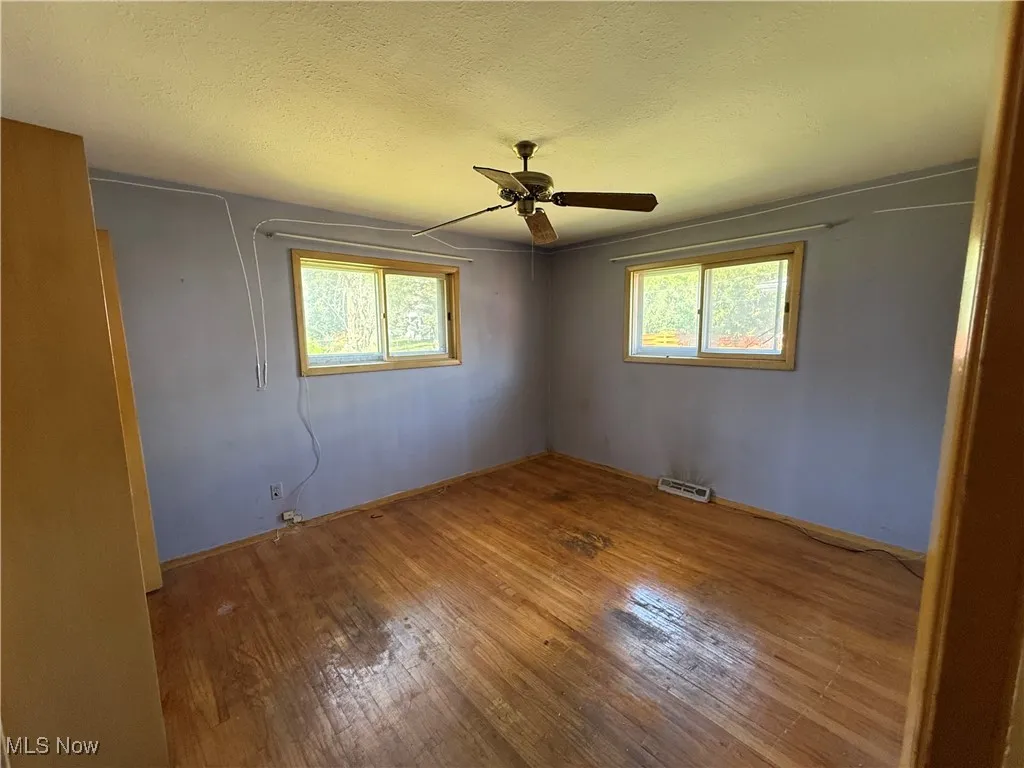Unfurnished bedroom featuring wood-type flooring, a textured ceiling, and ceiling fan
