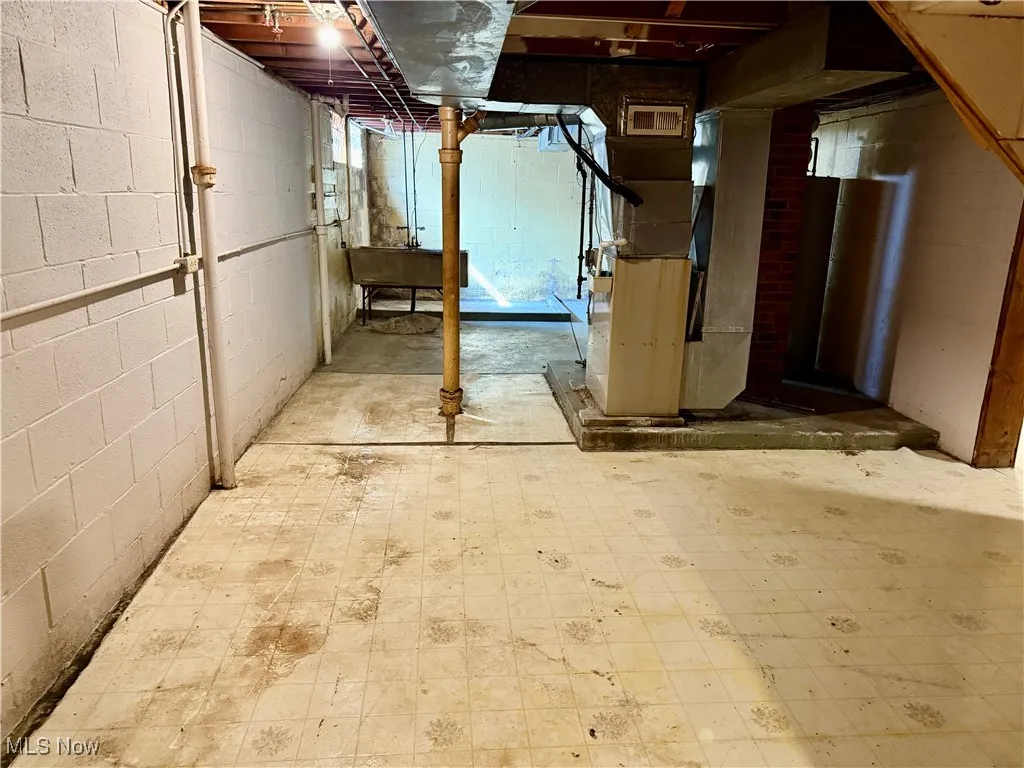 Unfinished basement featuring heating unit and tile patterned floors