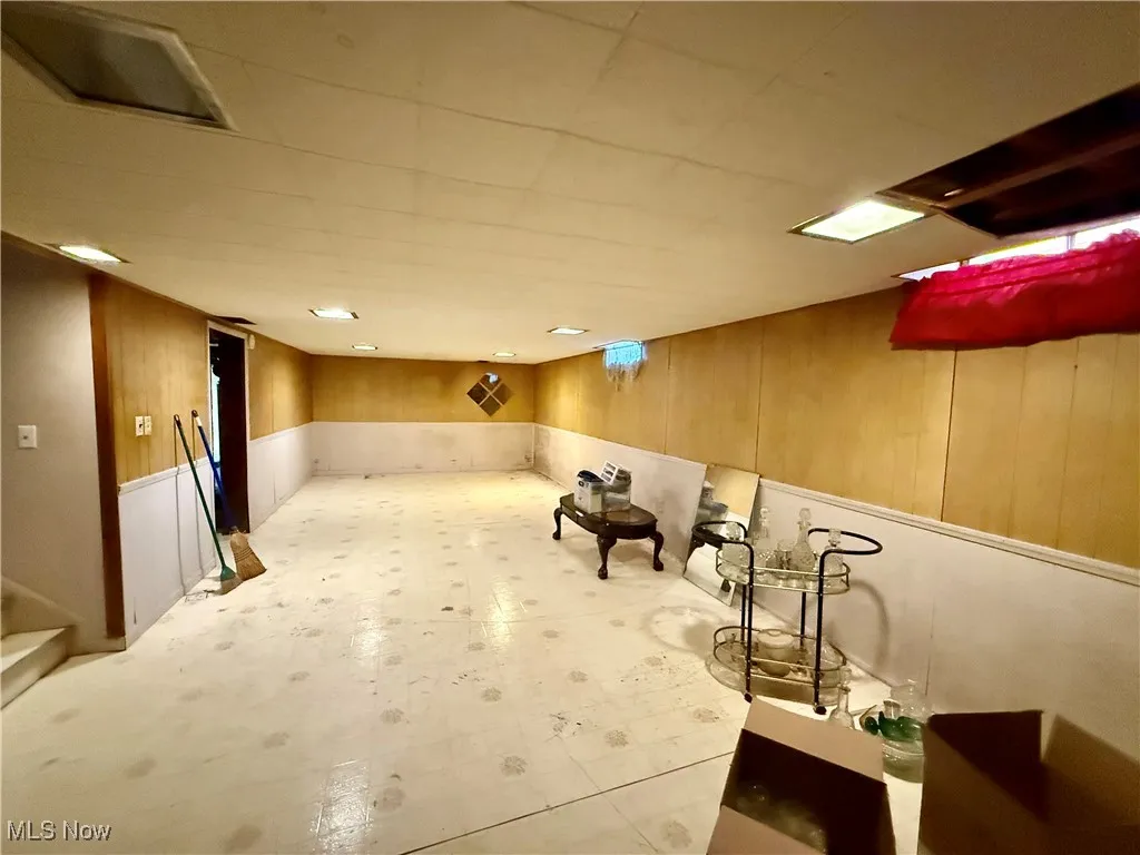 Finished below grade area featuring wooden walls, a wainscoted wall, and tile patterned floors