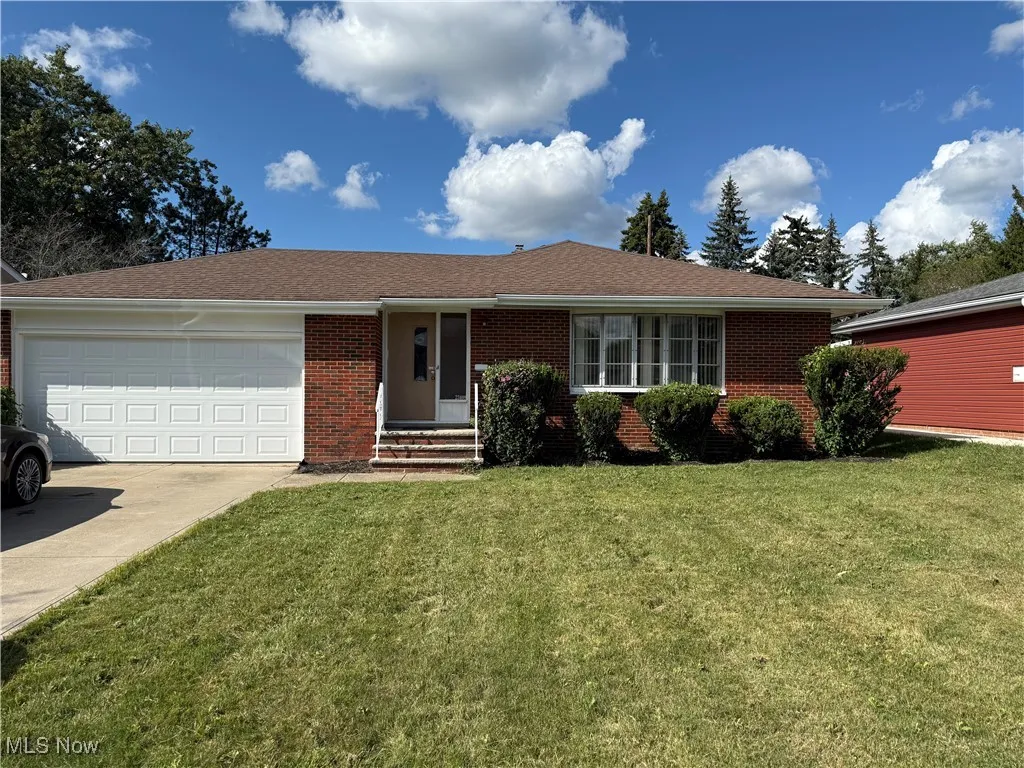 Single story home featuring a garage, brick siding, concrete driveway, and a front yard