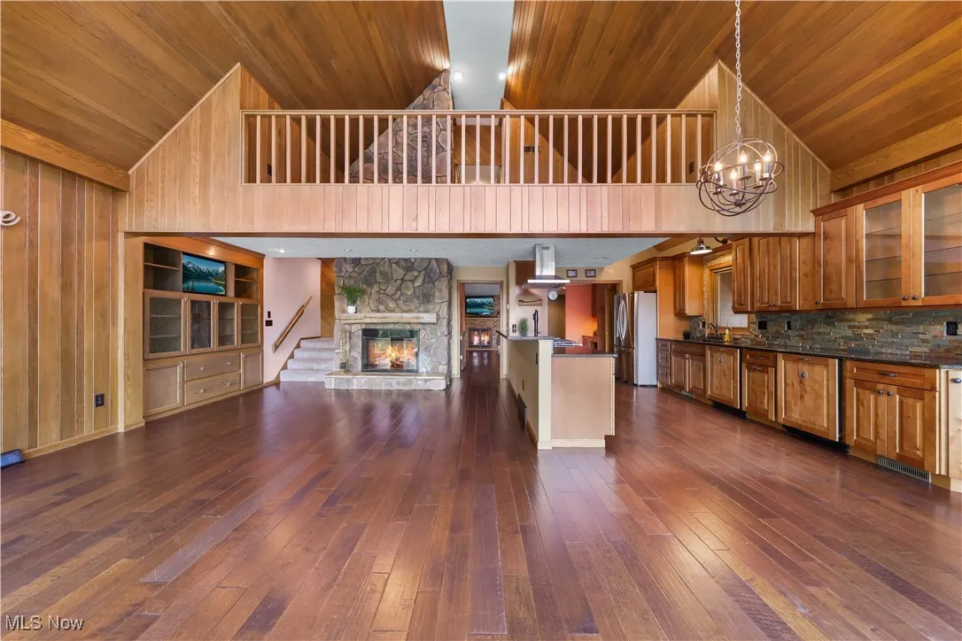 Dining room with views of the loft, open floor plan, floor-to-ceiling stone fireplace, and built-in cabinetry with TV.