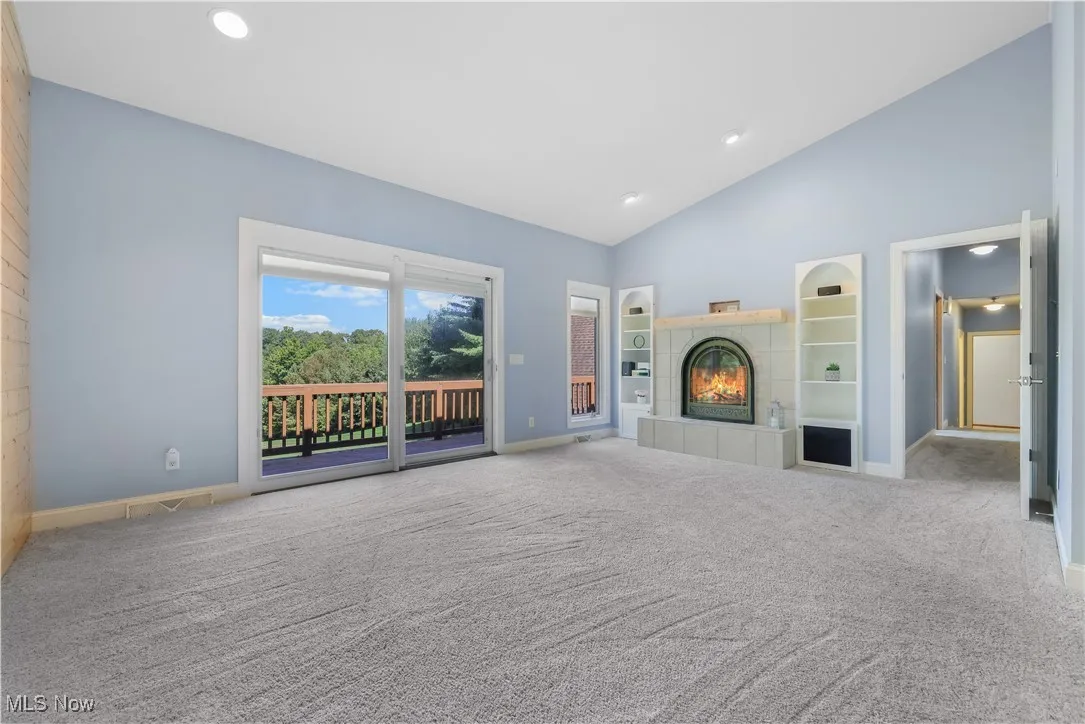 Primary bedroom,  a fireplace w built-in shelving, vaulted ceilings and access to the balcony