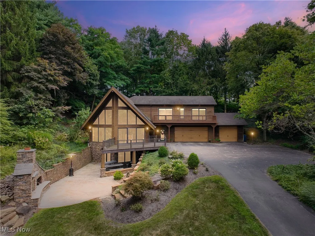 View of front facade - A-frame contemporary with rustic charm, outdoor stone fireplace, patio on LL, deck, 3-car garage (3rd bay has a raised roof to accommodate a large van or small RV) and driveway w/ turnaround.