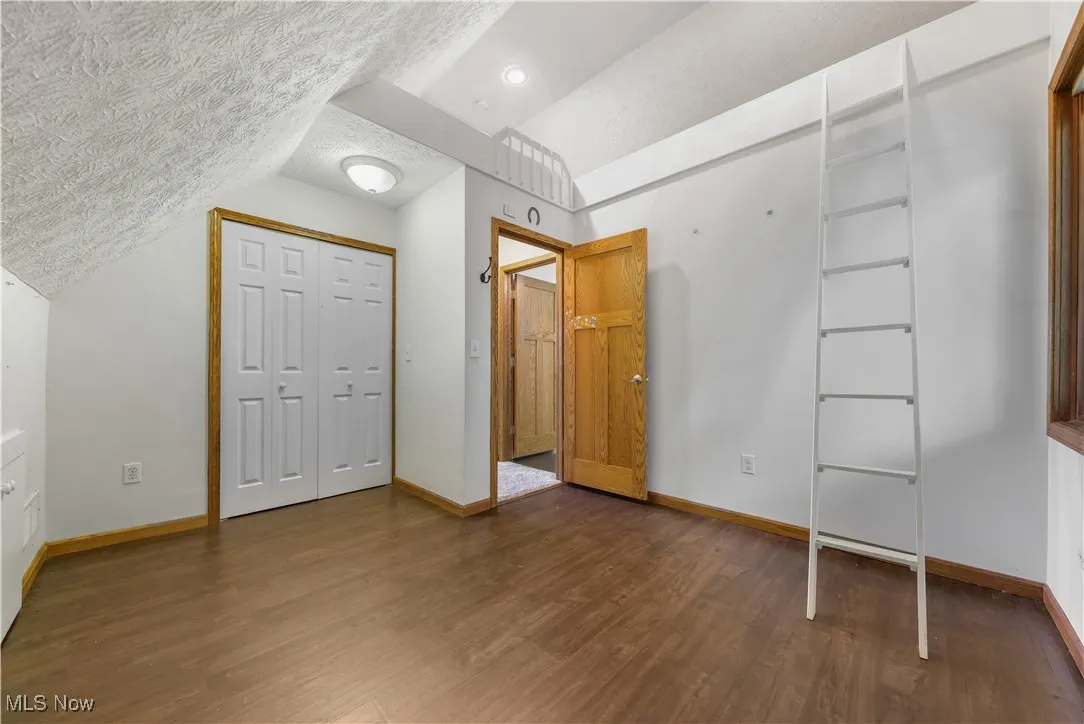 Kids bedroom with a vaulted, lofted bed area w ladder, a closet, and wood flooring