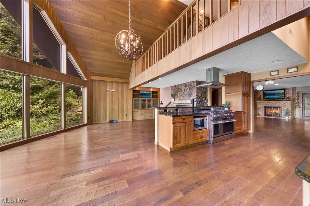 Kitchen with granite counters, island range hood, gorgeous floor-to-ceiling windows, chandelier and planked ceiling