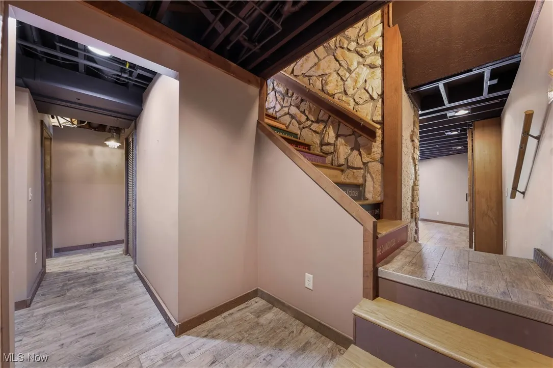 LL hallway leading to the 4th bedroom (2nd living suite) featuring stone wall and stairs with custom-painted names of famous books