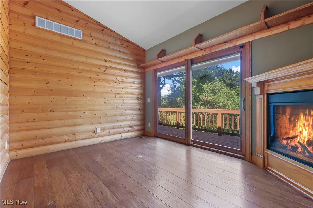 Den with lofted ceiling, rustic log cabin walls, fireplace and access to the balcony