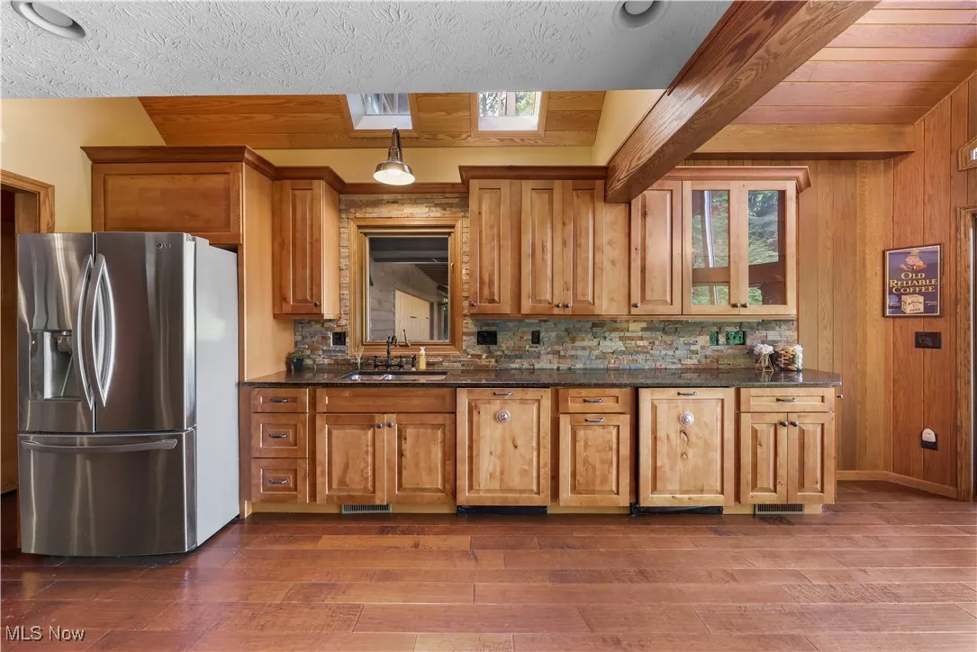 Kitchen with rustic cabinetry, 2 dishwashers, granite countertops, stone backsplash, stainless, high-end appliances with vaulted plank ceilings