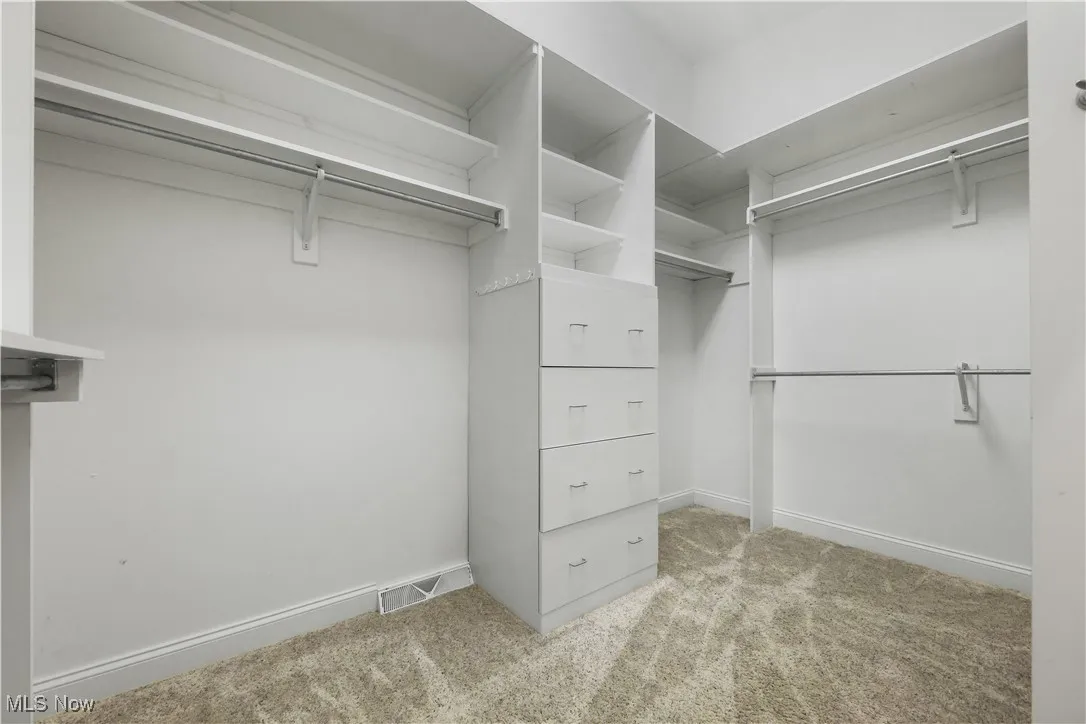 Spacious, primary walk-in closet with built-in cabinetry