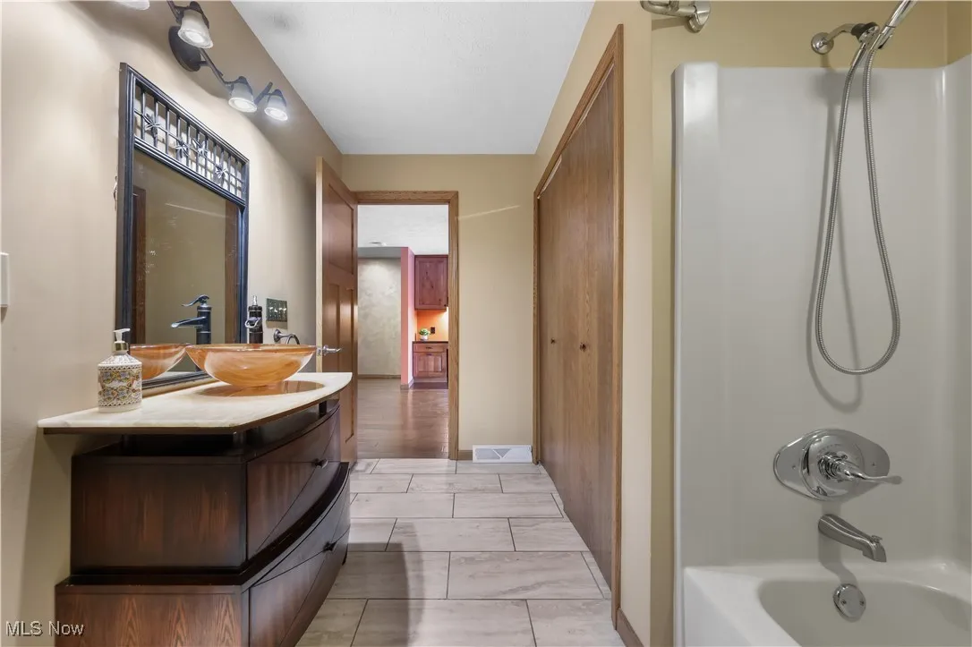 First floor full bathroom featuring vanity, shower / bath combination and large linen closet