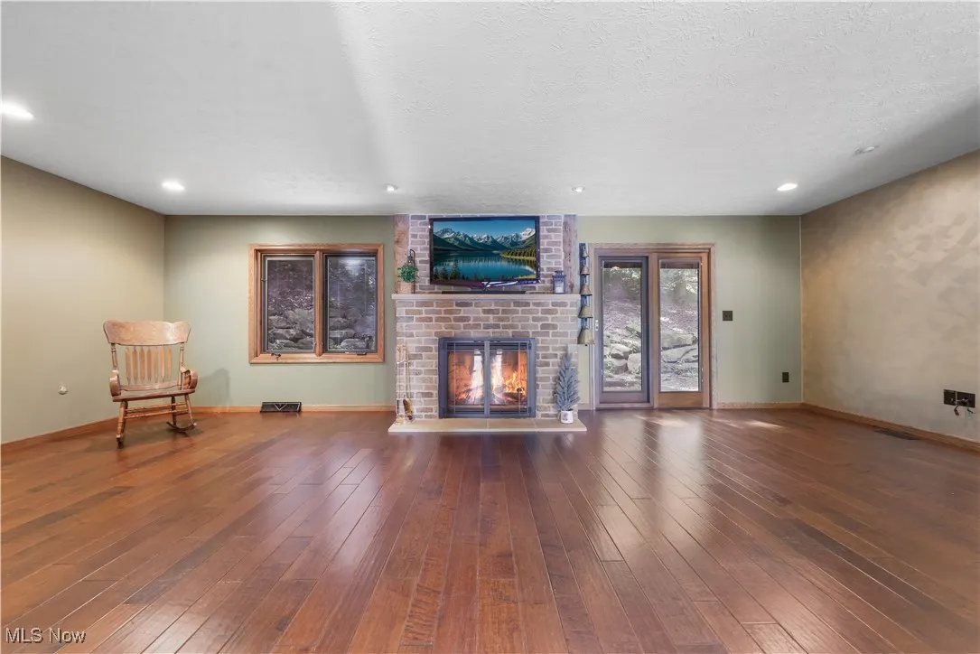 Family room with a fireplace, wood flooring, recessed lighting, and access to the backyard. Landscaping rock wall was a $30k upgrade