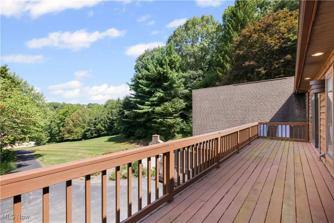 View of balcony off the primary suite and den overlooking the picturesque front yard