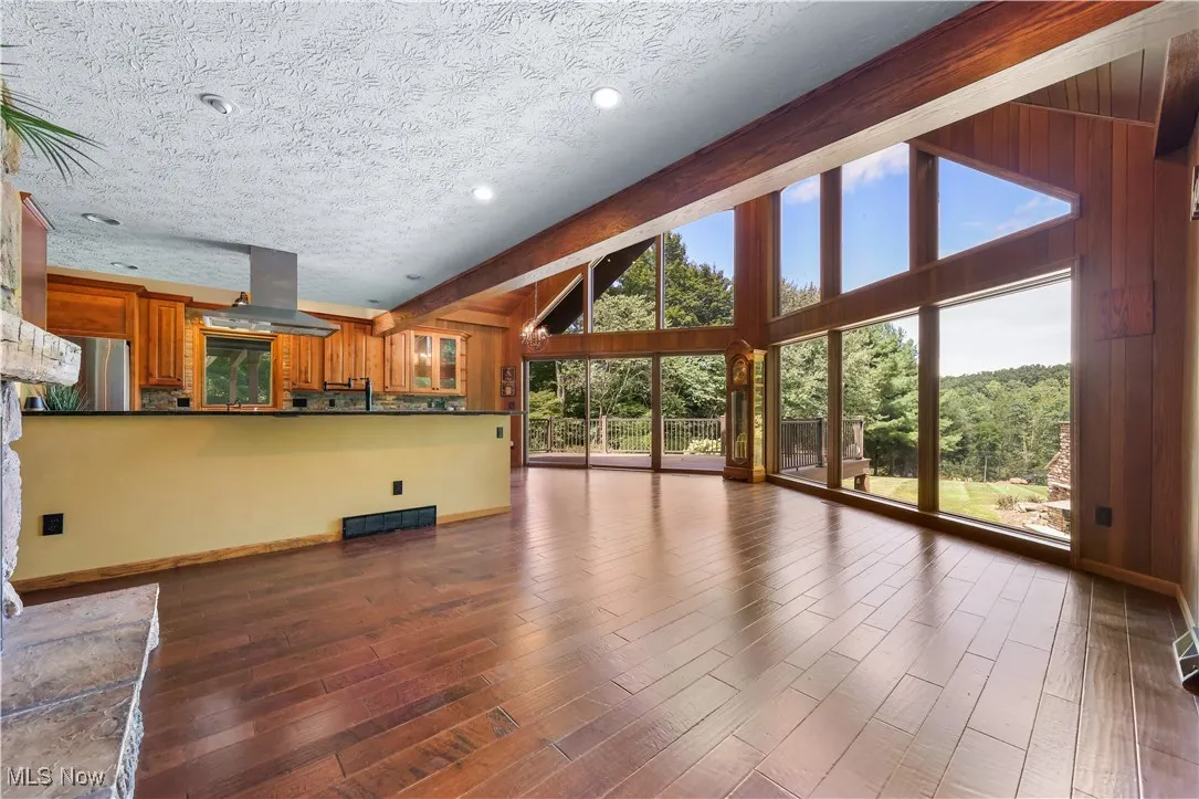 Dining room featuring high ceiling, deck, an A-frame wall of windows that overlooks the gorgeous scenery including the outdoor stone fireplace feature. Grandfather clock conveys.