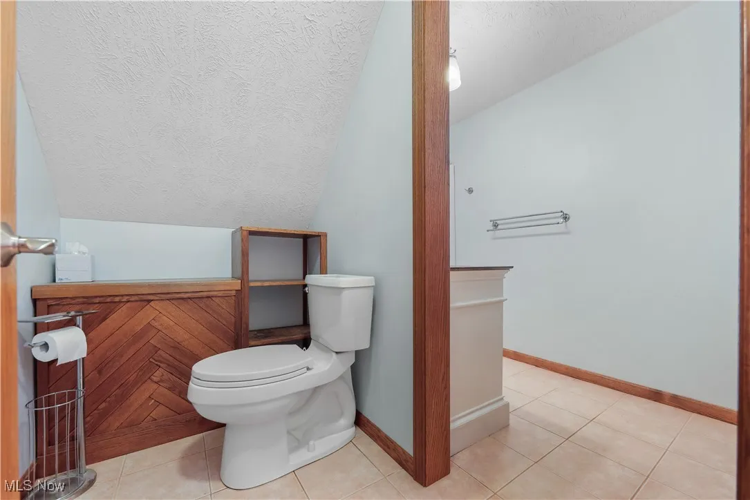 Full bath featuring vaulted ceiling, and tile floors
