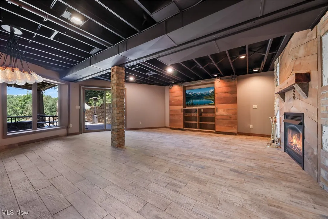 LL recreation room with a large fireplace, built-in shelving, mounted TV, fireplace and walk-out to patio