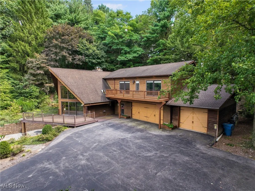 Rustic home featuring a 30 year roof, driveway, 3 car garage w/raised roof to accommodate an RV and a wooden deck