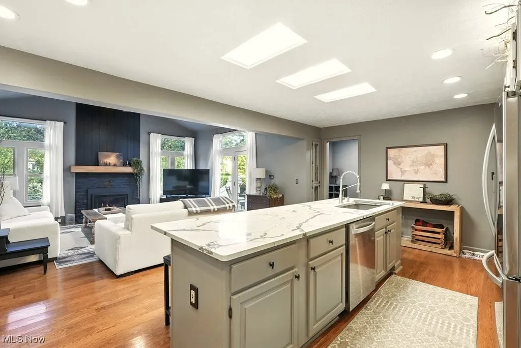 Kitchen with recessed lighting, light stone counters, a fireplace, light wood finished floors, and healthy amount of natural light