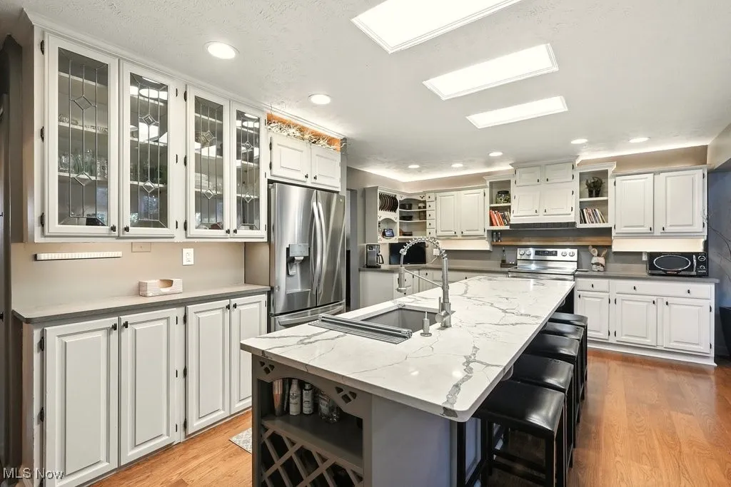 Kitchen featuring open shelves, white cabinets, recessed lighting, stainless steel appliances, and light wood-type flooring