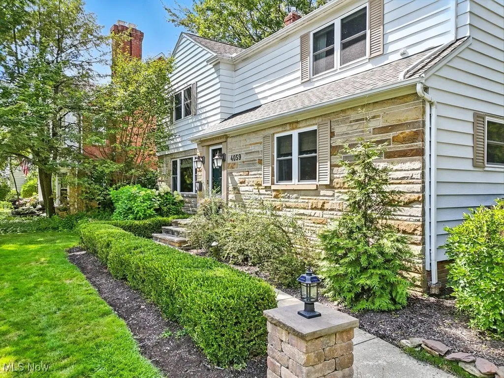 Doorway to property featuring stone siding, a chimney, and roof with shingles
