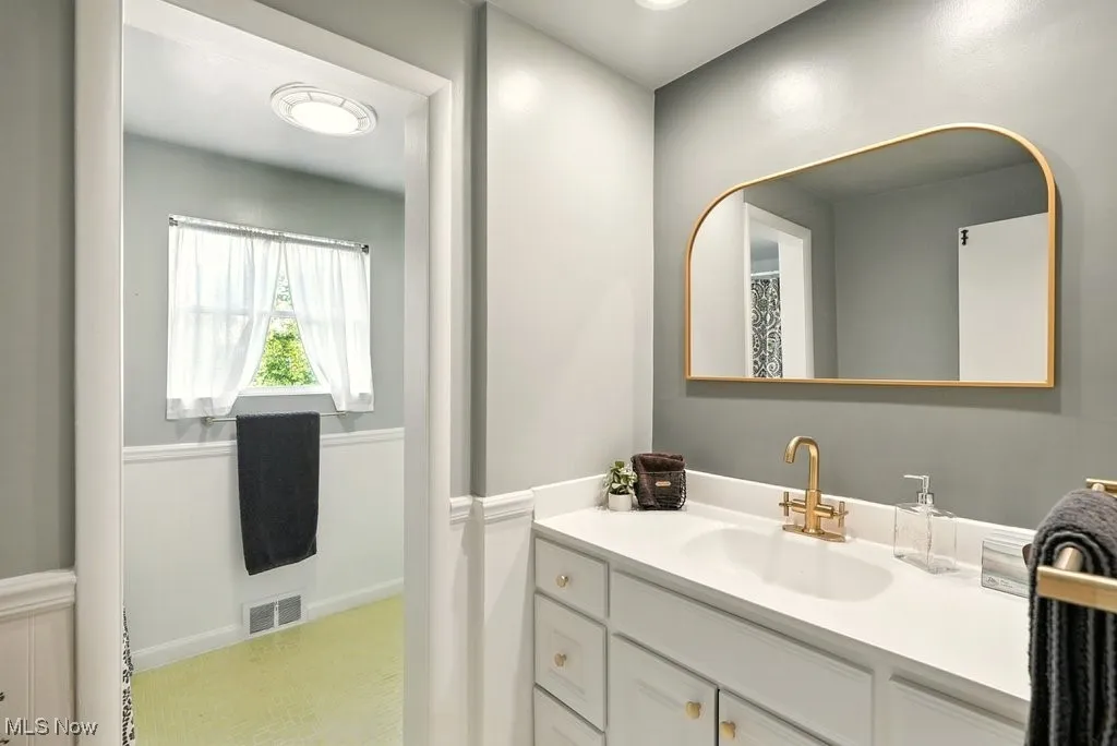 Full bath with vanity and wainscoting