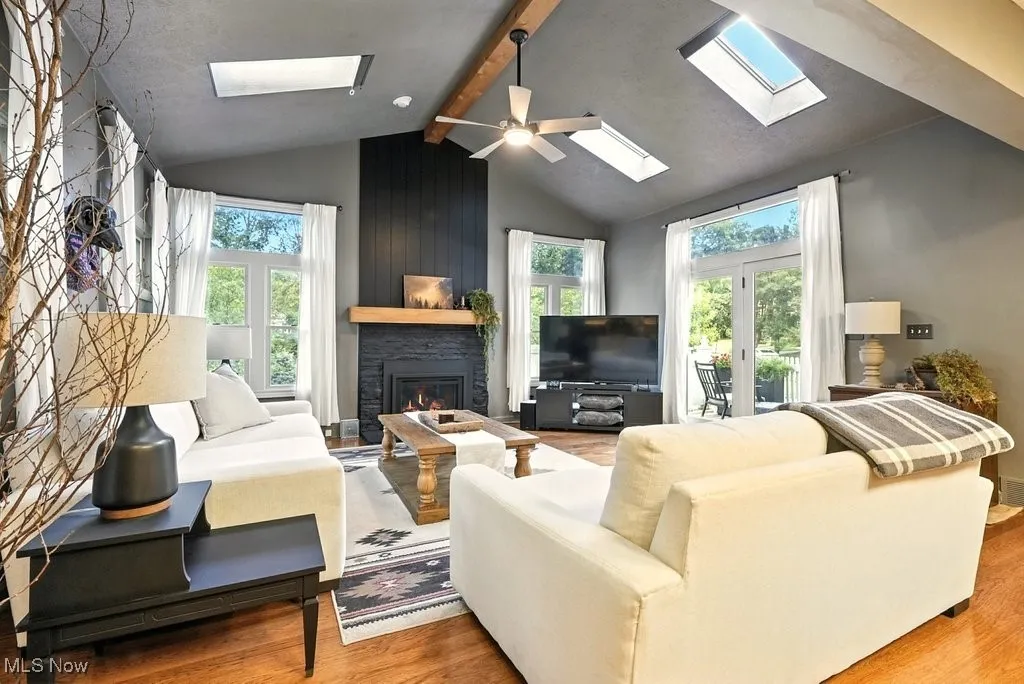 Living area with wood finished floors, a skylight, and a fireplace