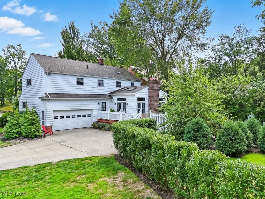 View of front of property with a garage, concrete driveway, a chimney, roof with shingles, and a deck