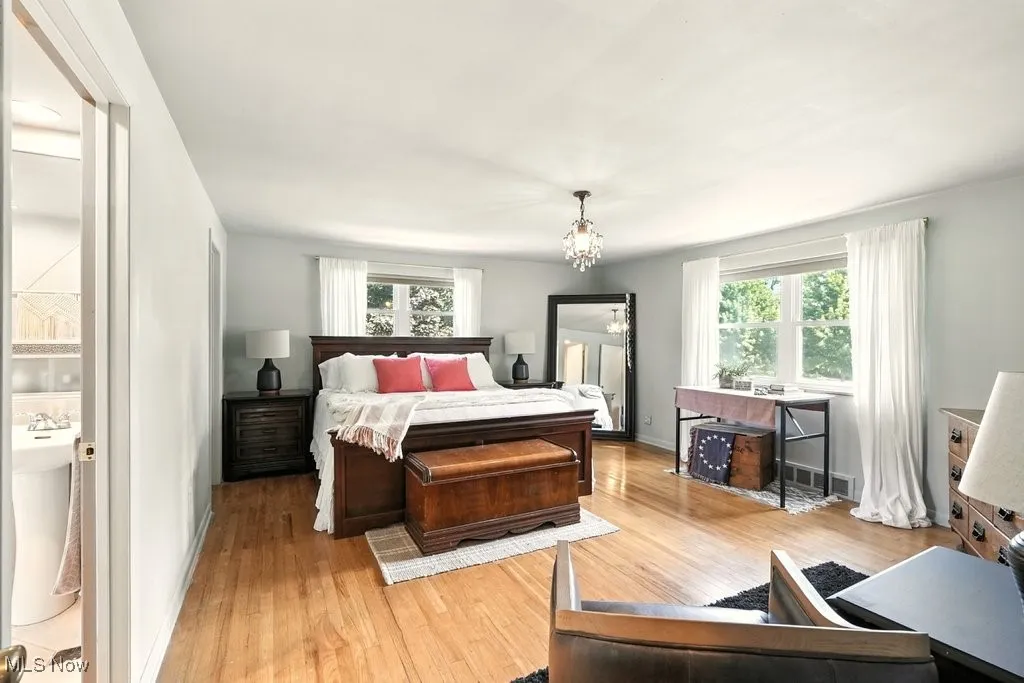 Bedroom featuring wood finished floors, a chandelier, and connected bathroom