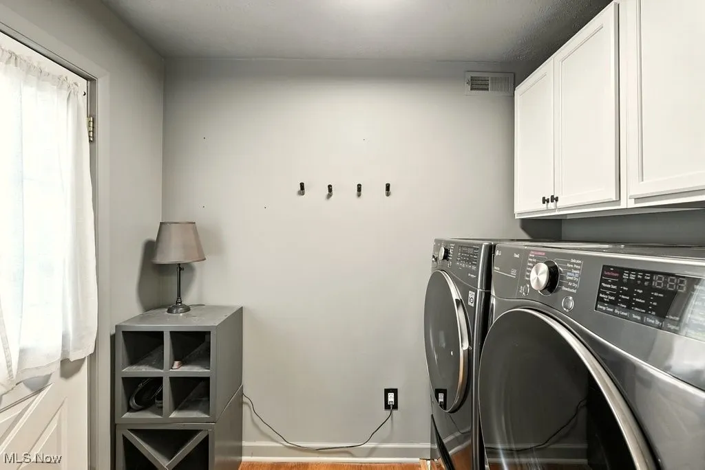 Laundry area with cabinet space, light wood-style floors, and washing machine and dryer