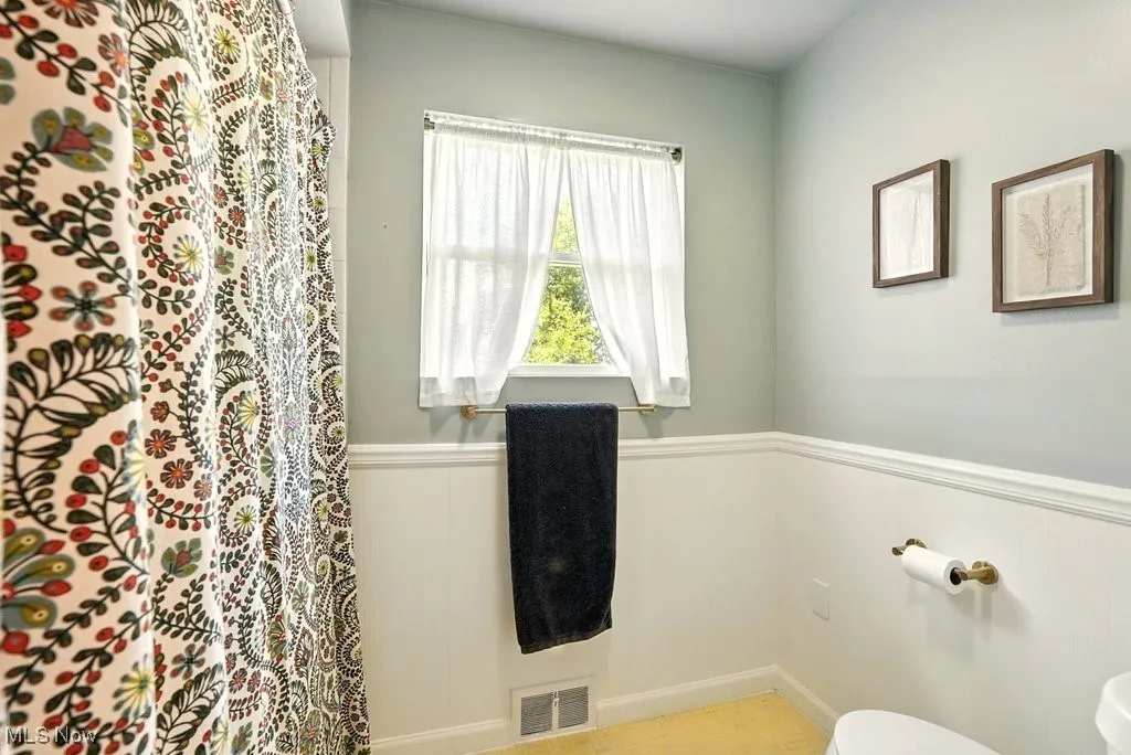 Bathroom with a wainscoted wall and toilet