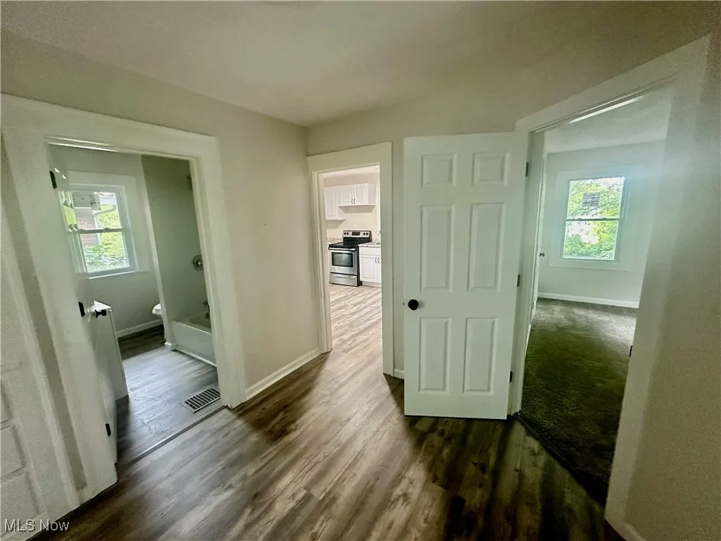 Hallway featuring dark wood finished floors and baseboards