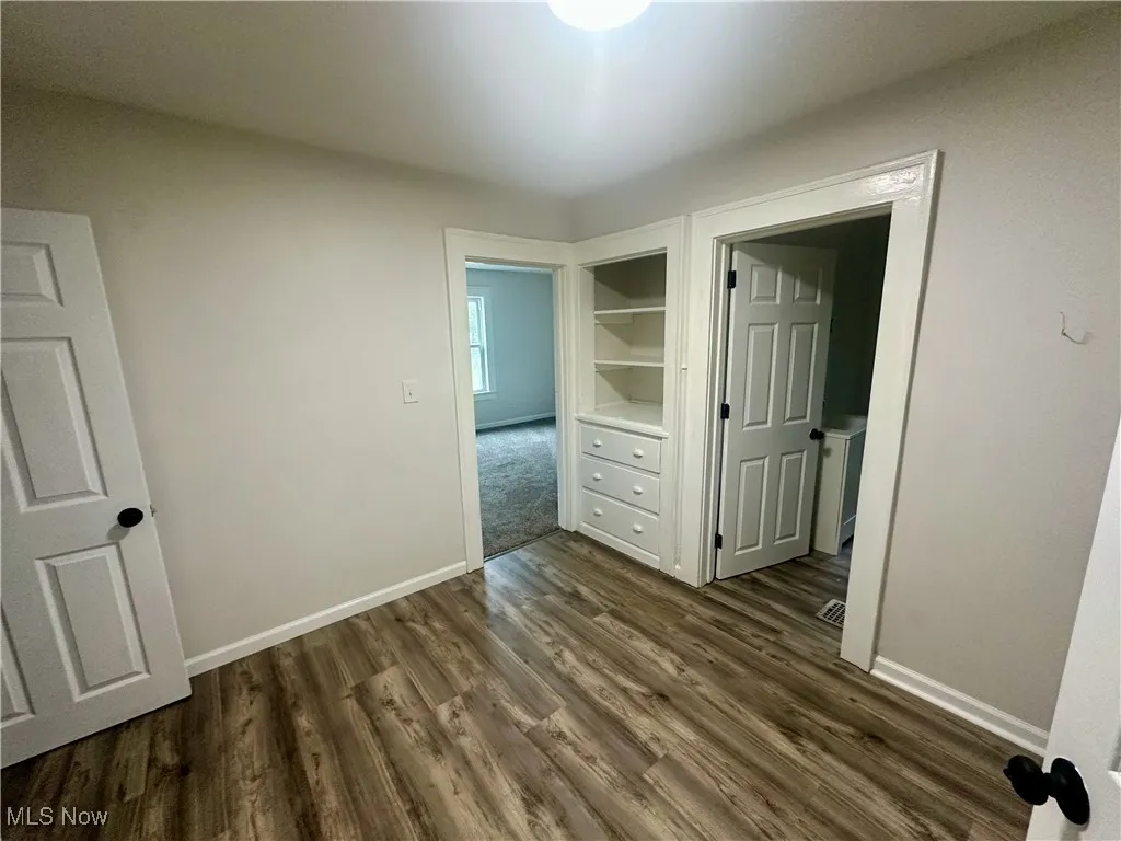 Unfurnished bedroom with baseboards and dark wood finished floors