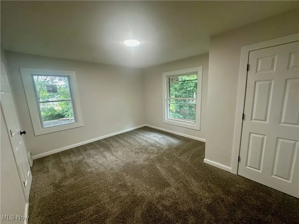 Empty room with baseboards and dark carpet