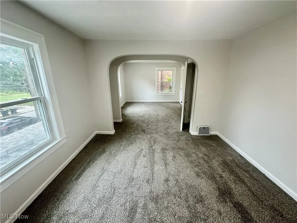 Carpeted spare room with baseboards and arched walkways