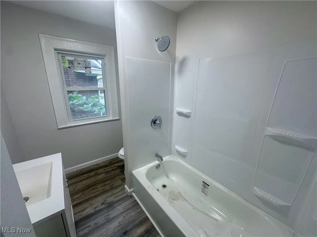 Full bathroom with  shower combination, vanity, and dark wood-type flooring