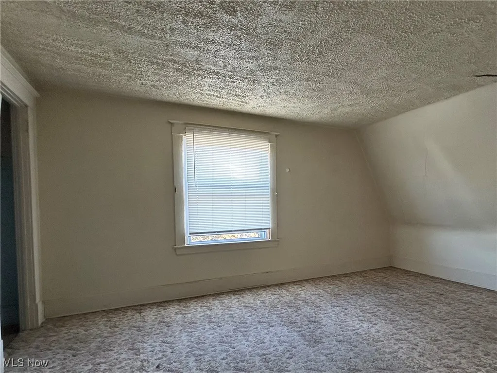 Additional living space with a textured ceiling and baseboards