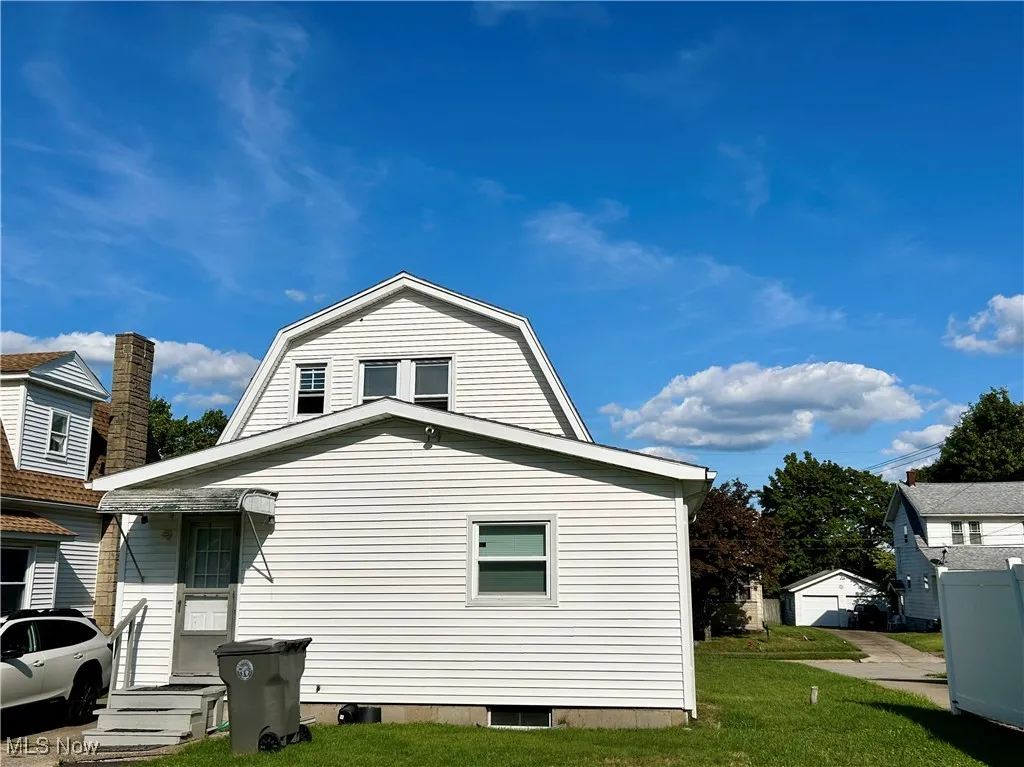 View of property exterior featuring a gambrel roof and a yard