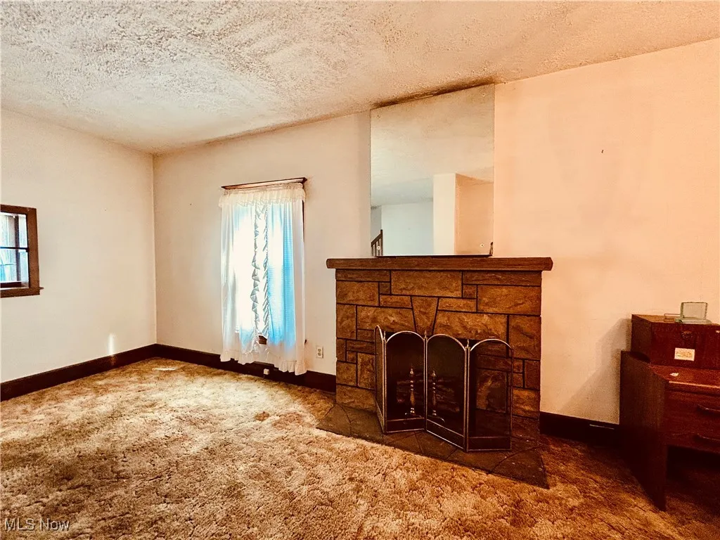 Unfurnished living room featuring a fireplace, a textured ceiling, and carpet floors