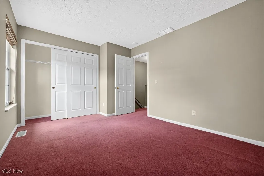 Unfurnished bedroom with carpet floors, a textured ceiling, and a closet