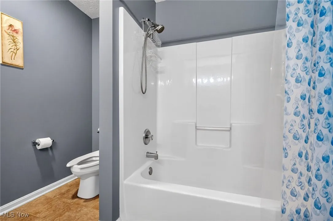 Full bath featuring shower / bath combo with shower curtain, tile patterned floors, and a textured ceiling