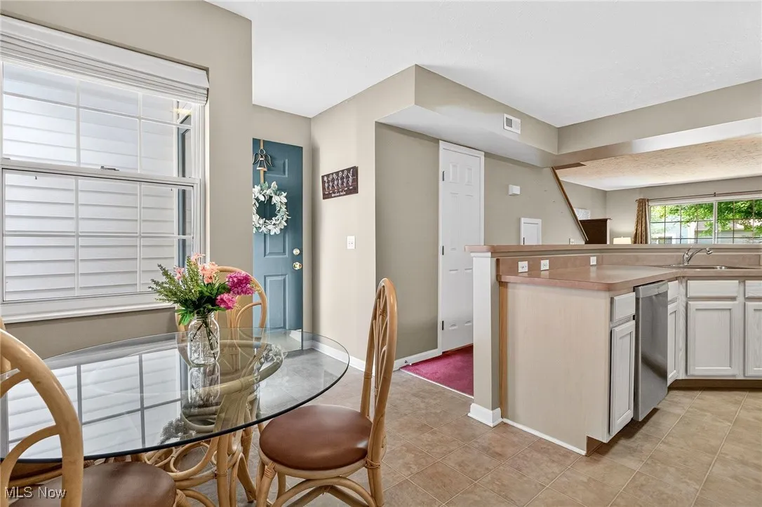 Kitchen featuring light countertops, white cabinetry, light tile patterned flooring, and stainless steel dishwasher