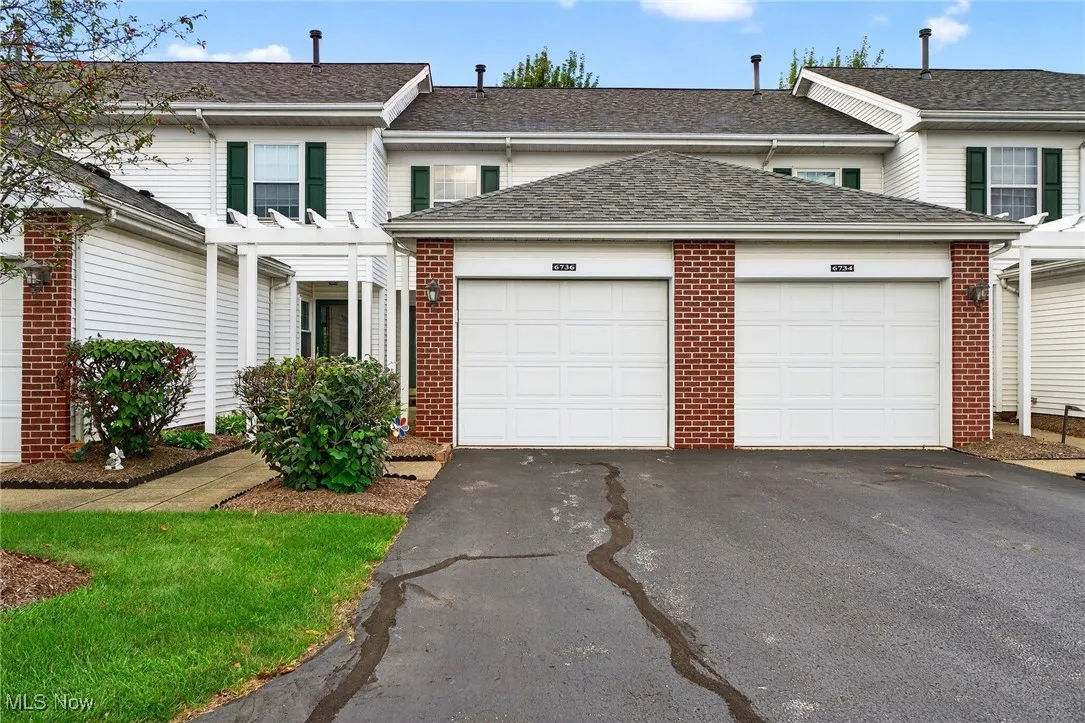 Traditional home with driveway, a shingled roof, an attached garage, and brick siding