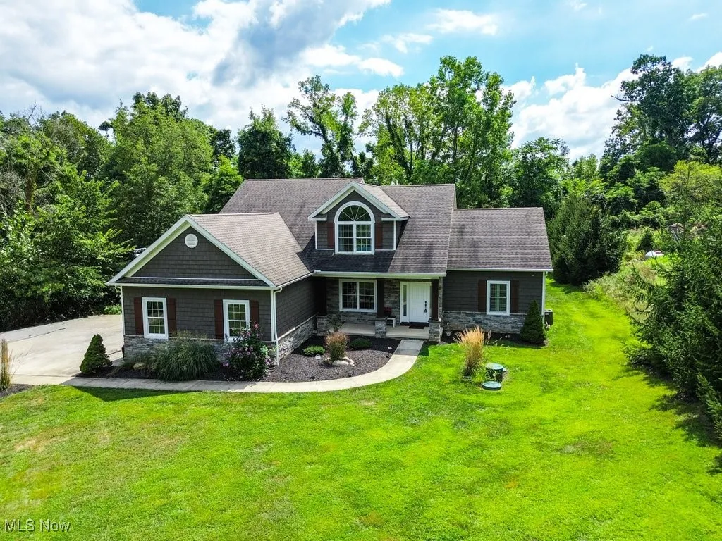 View of front of property featuring stone siding, covered porch, a front yard, and roof with​​‌​​​​‌​​‌‌​‌‌​​​‌‌​‌​‌​‌​​​‌​​ shingles
