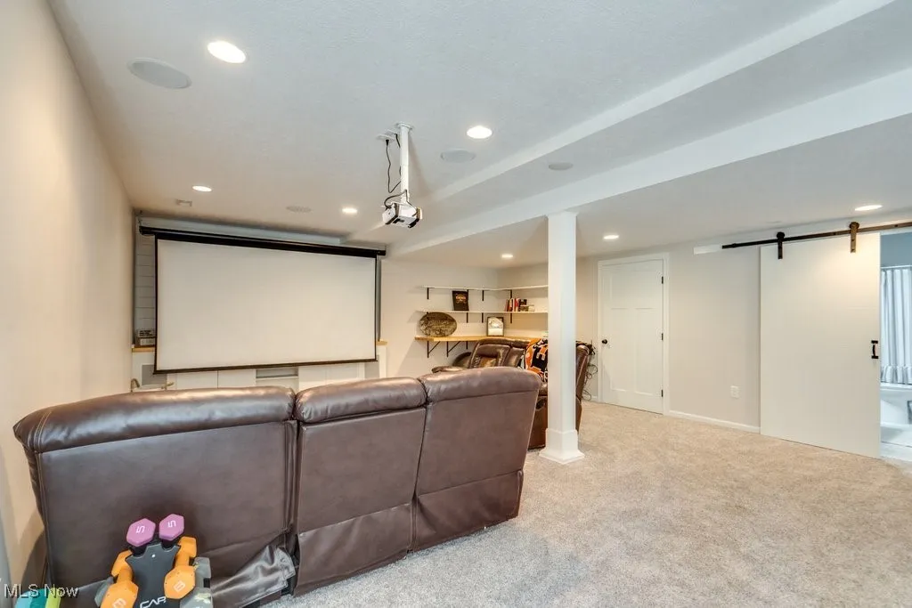 Cinema featuring a barn door, recessed lighting, and light colored carpet