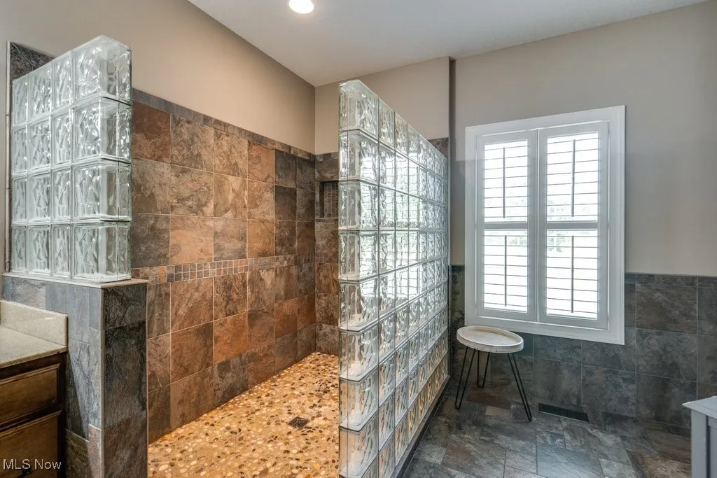 Full bath featuring walk in shower, tile walls, a wainscoted wall, recessed lighting, and vanity