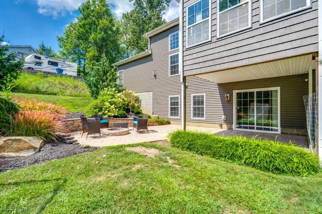View of green lawn featuring a patio and an outdoor fire pit
