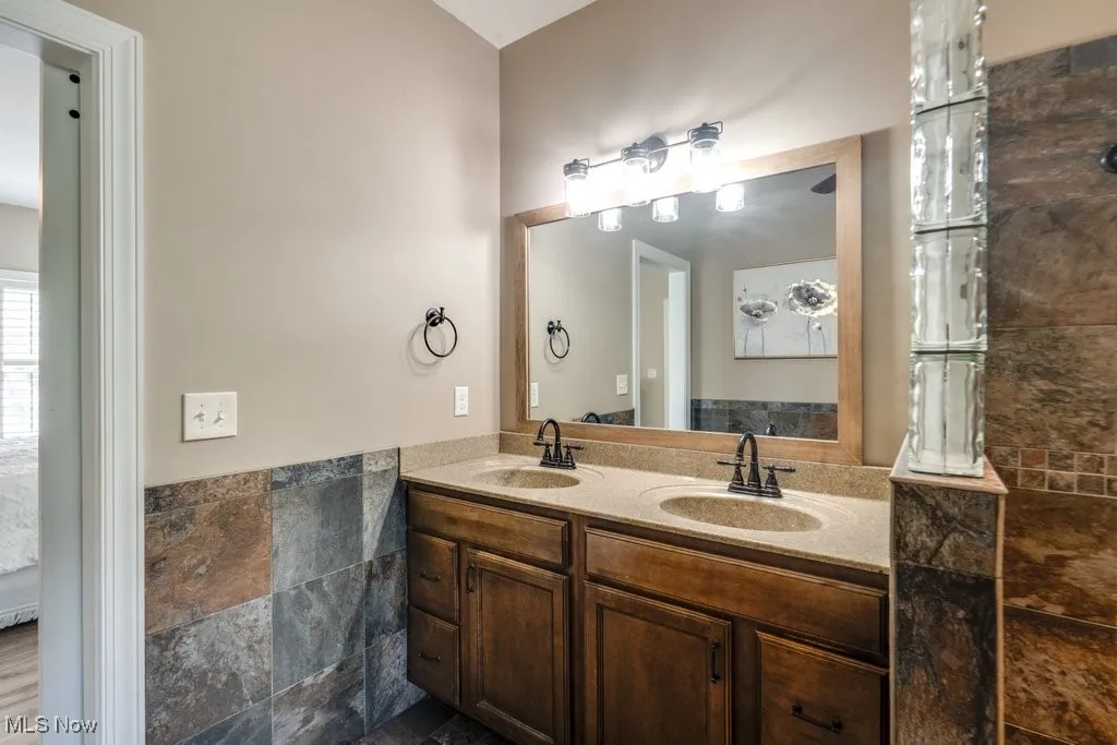 Bathroom with double vanity and tile walls