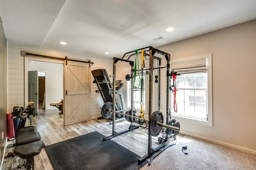 Workout area with wood walls, recessed lighting, a barn door, and wood finished floors