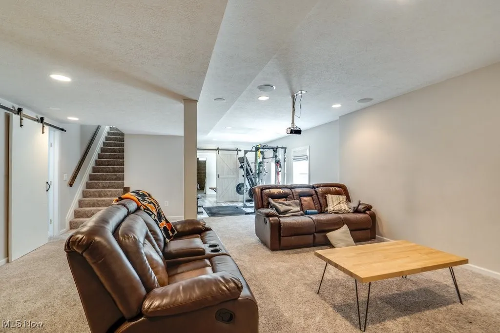 Carpeted living area featuring a barn door, a textured ceiling, and recessed lighting
