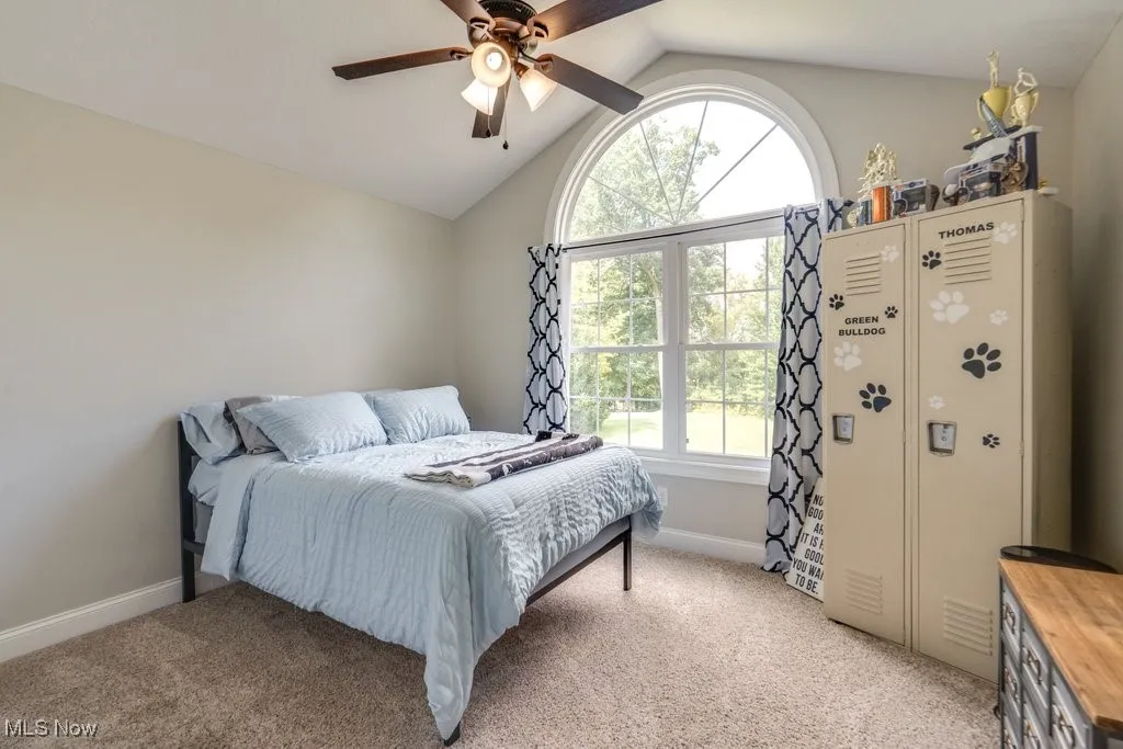 Bedroom with light colored carpet, lofted ceiling, and a ceiling fan