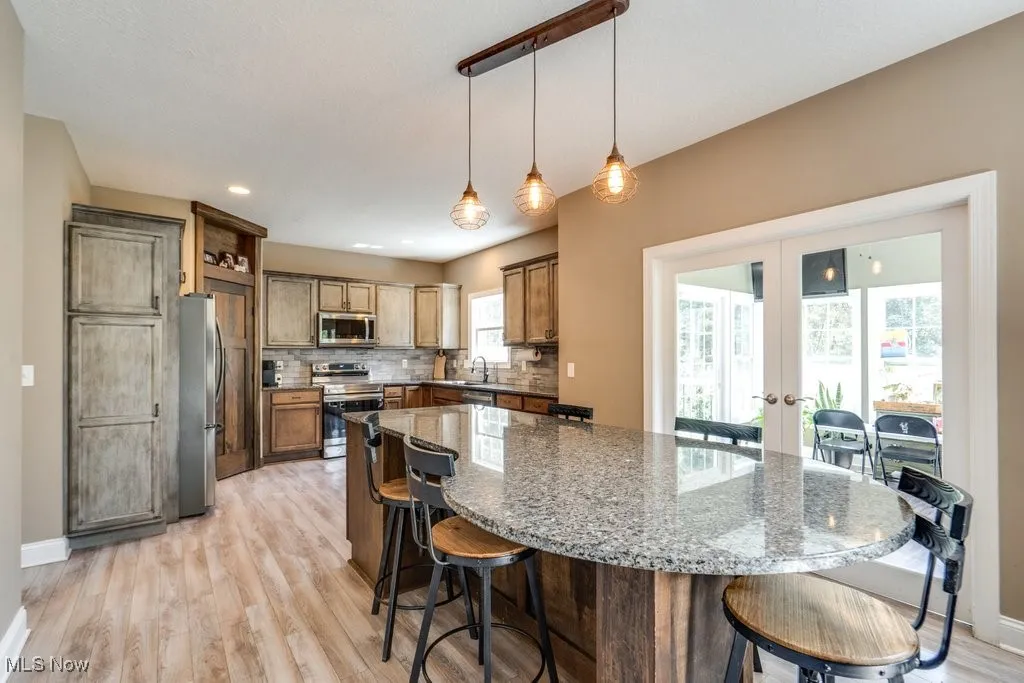 Kitchen featuring a kitchen breakfast bar, french doors, dark stone countertops, pendant lighting, and recessed lighting
